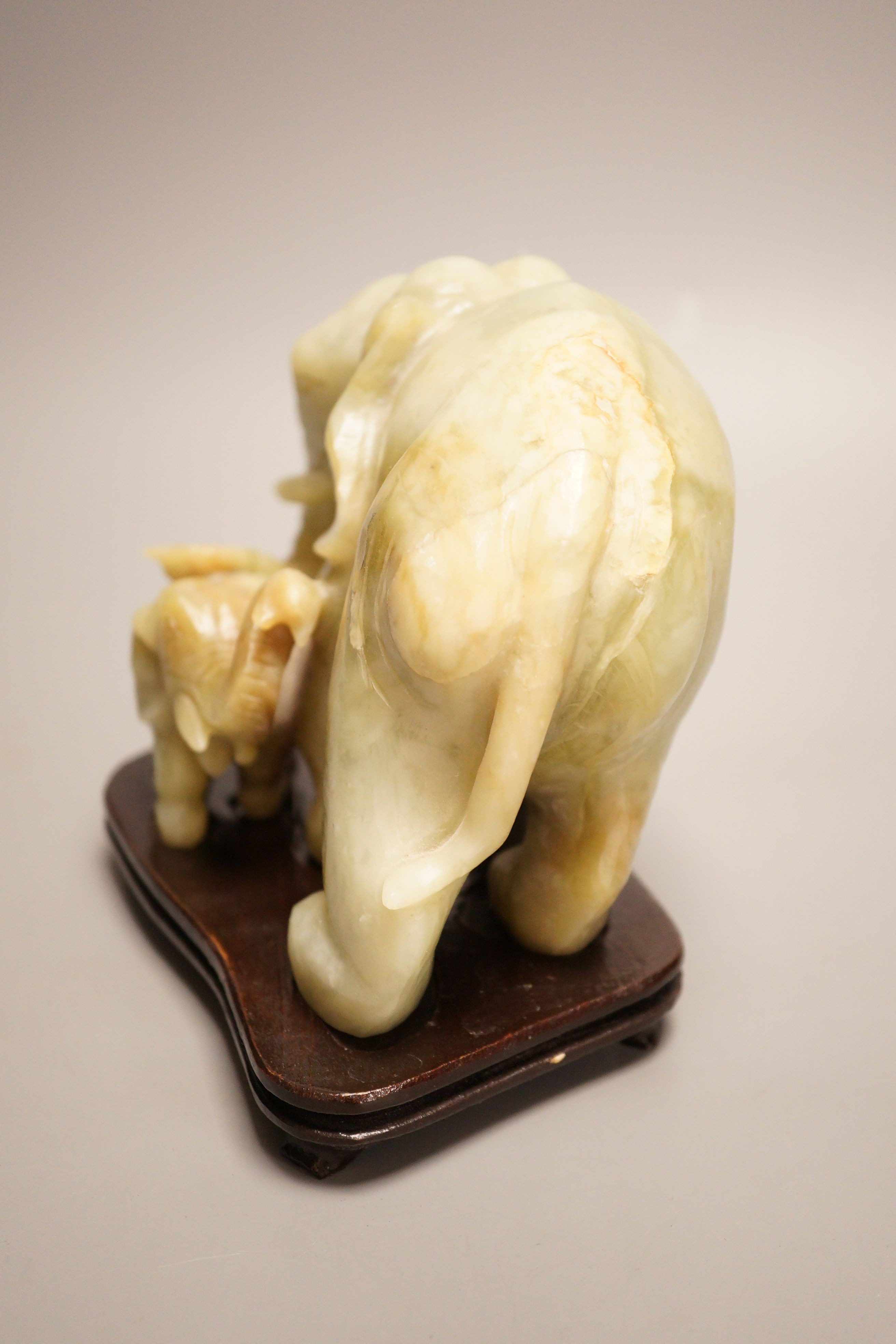 A Chinese carved bowenite ‘elephant’ group on hardwood stand, 15cm
